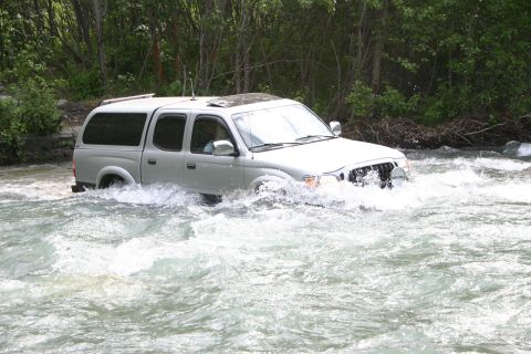 2003 Jeep TJ - A silver Toyota Tacoma pickup truck navigates through a fast-flowing river.
