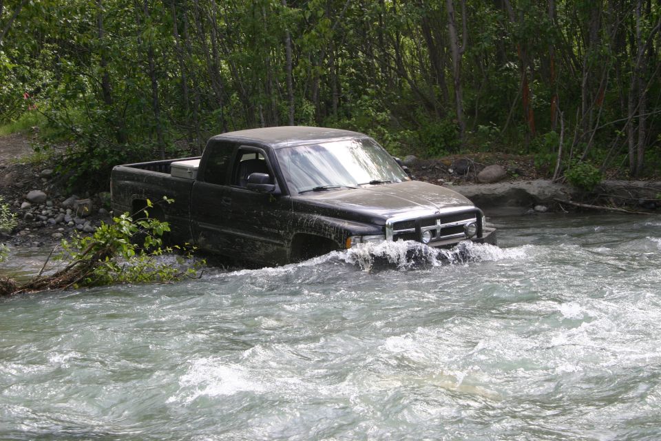 Black pickup truck driving through a river, front view