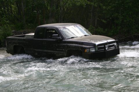 2003 Jeep TJ - A black pickup truck navigates through a fast-moving river.