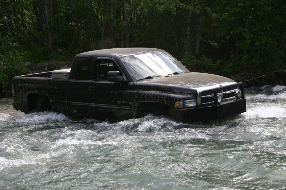 Black pickup truck driving through a river, front bumper and grille visible