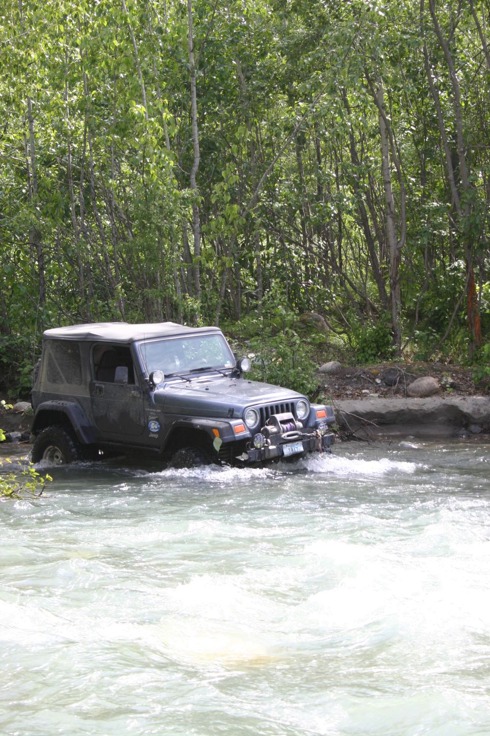 Dark gray 2003 Jeep Wrangler TJ driving through a river