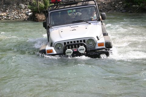 2003 Jeep TJ - A silver Jeep TJ navigates a rocky riverbed, its front end partially submerged in the flowing water.