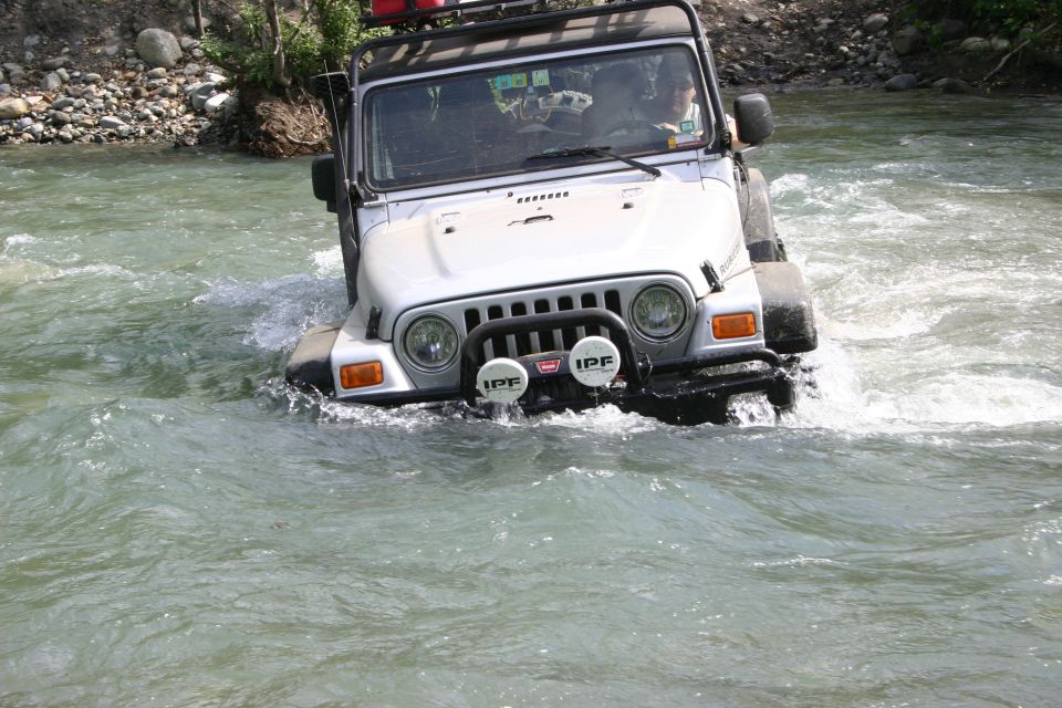 Silver Jeep TJ driving through river, IPF lights visible
