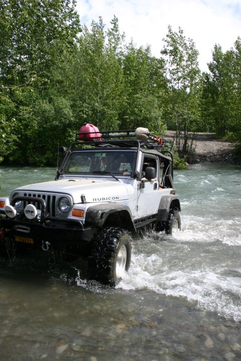 2003 Jeep TJ - 2003 Jeep TJ Wrangler Rubicon navigates a river crossing with off-road gear on the roof.