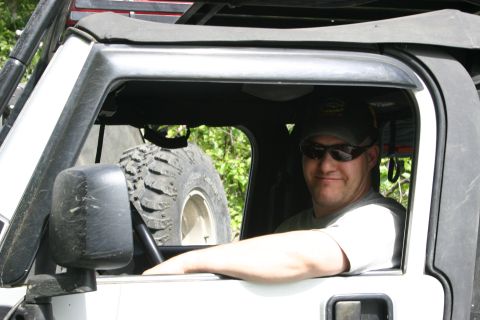 2003 Jeep TJ - A man smiles from the driver's seat of a white Jeep TJ, with a spare tire visible behind him.