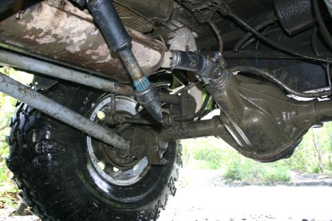 2003 Jeep TJ - Close-up view of the undercarriage of an off-road vehicle, showing the rear axle, driveshaft, and a large tire.
