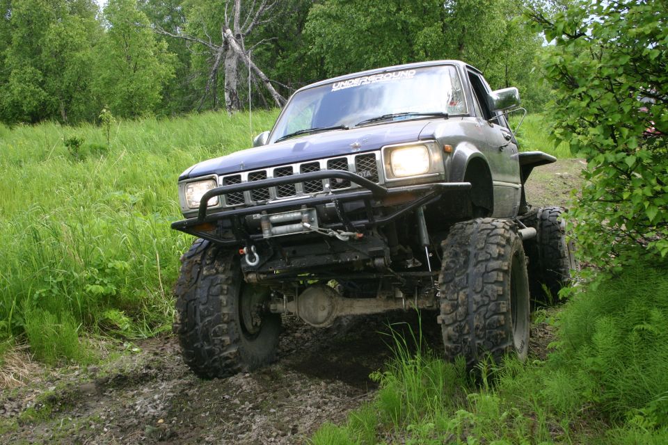 Modified pickup truck with large tires and winch on a dirt trail