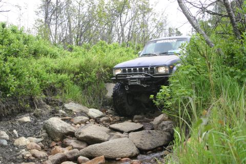 2003 Jeep TJ - Off-road SUV carefully maneuvers through a challenging rocky stream bed.