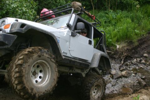 2003 Jeep TJ - This 2003 Jeep TJ is tackling a challenging off-road trail with mud and rocks.