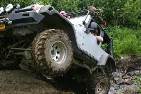 2003 Jeep TJ - This modified Jeep TJ navigates a challenging off-road trail with steep, muddy terrain.