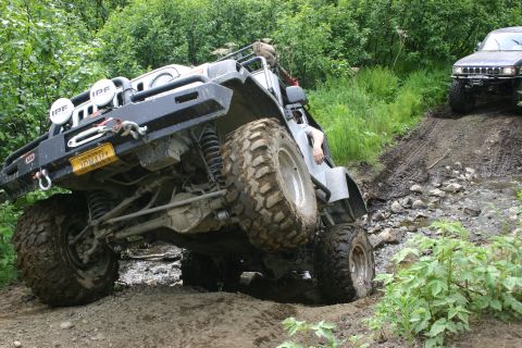 2003 Jeep TJ - A Jeep Wrangler navigates a challenging muddy off-road course with another vehicle following behind.