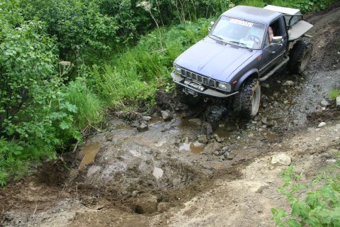 2003 Jeep TJ - Pickup truck attempts to cross a muddy obstacle on an off-road trail.
