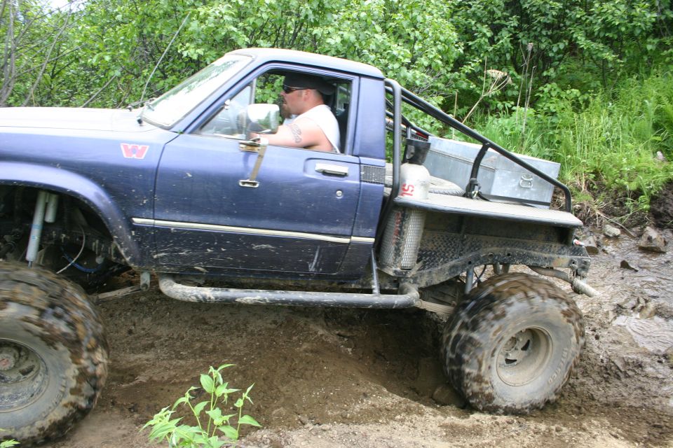 Blue pickup truck with large tires navigating muddy terrain
