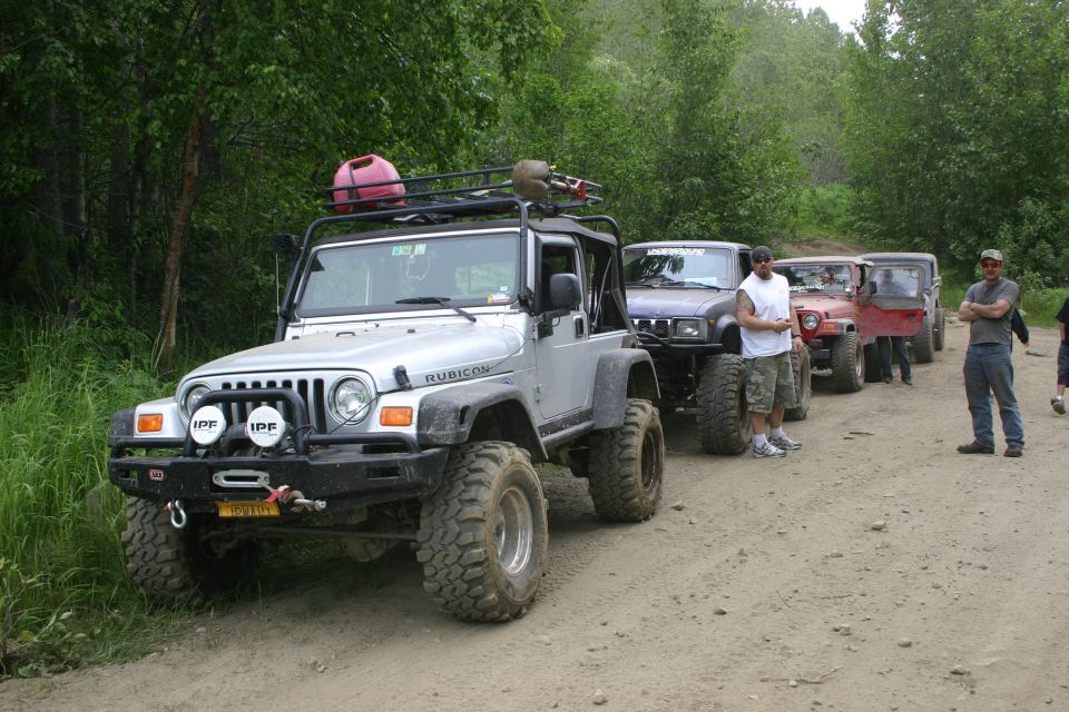 Silver Jeep Wrangler TJ Rubicon with winch bumper and roof rack leading a trail convoy on a dirt road