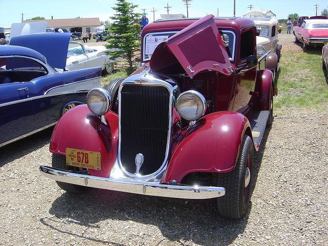 Maroon pickup truck with hood open, chrome grille, and yellow New Mexico license plate 678