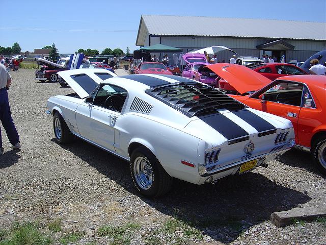 1967 Ford Mustang fastback with black stripes and louvers, parked at an outdoor car show