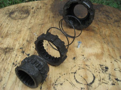 1991 Ford Bronco - Disassembled Warn Premium hubs are laid out on a wooden surface, showing the internal components and a small screw.