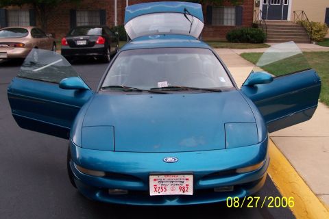 1994 Ford Probe - A blue 1994 Ford Probe is parked with its doors and trunk open, showing the front of the vehicle.