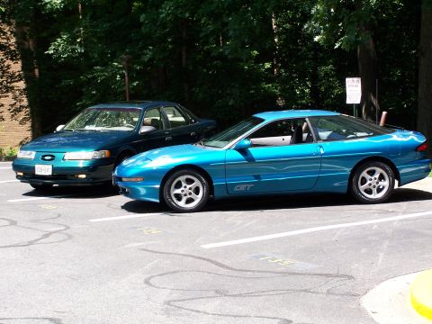 1994 Ford Probe - A blue 1994 Ford Probe GT is parked next to a dark sedan in a lot.