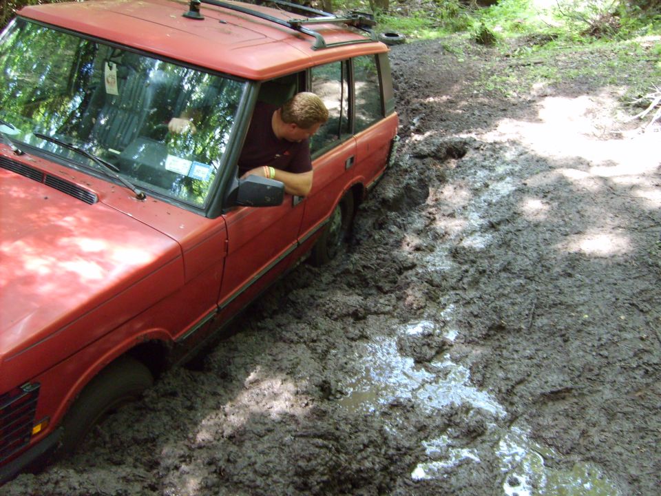 Red Range Rover stuck in mud, driver looking out window