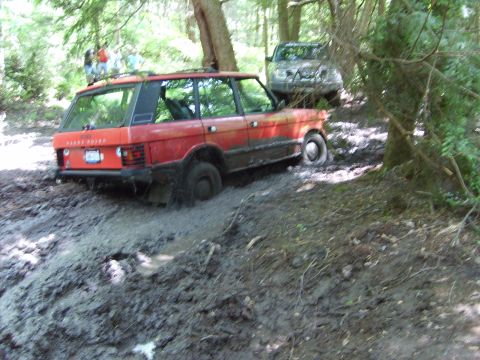 1995 Ford Bronco - Two SUVs navigate a muddy trail, with the lead Range Rover deeply stuck in the mire.