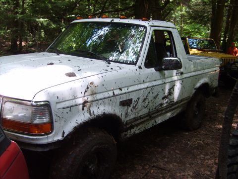 1995 Ford Bronco - White 1995 Ford Bronco covered in mud after off-roading in a wooded area.