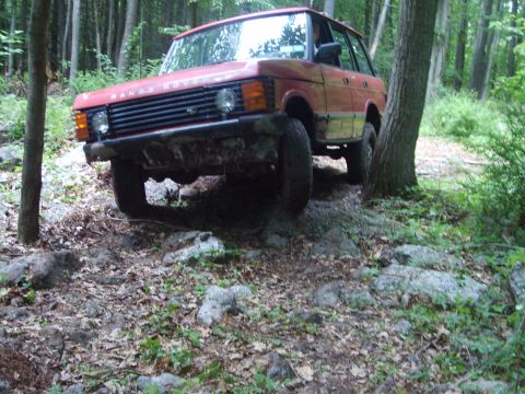 1995 Ford Bronco - This Range Rover is navigating a rocky path through a forest.