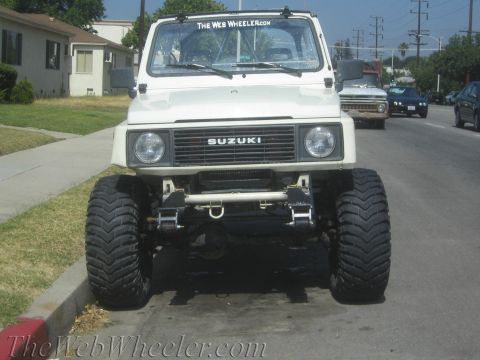 1987 Suzuki Samurai - This modified Suzuki Samurai features oversized tires and a prominent "The Web Wheeler.com" sticker on the windshield.