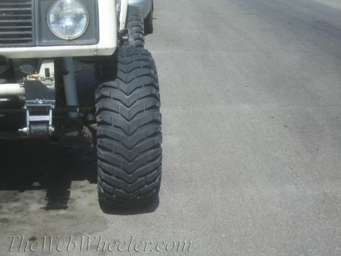 1987 Suzuki Samurai - Detail shot of a vehicle's front tire and suspension system, showing off-road modifications.