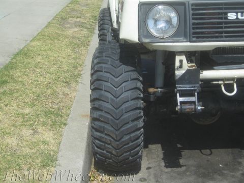 1987 Suzuki Samurai - Close-up of the front wheel and suspension of a Suzuki Samurai, showing its off-road tire.