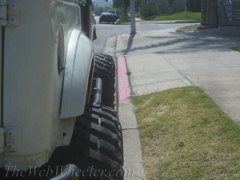 1987 Suzuki Samurai - Side profile of a white off-road vehicle with aggressive tires parked curbside.
