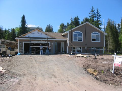 1984 Ford Bronco - House construction site with scaffolding around the garage and siding being installed.
