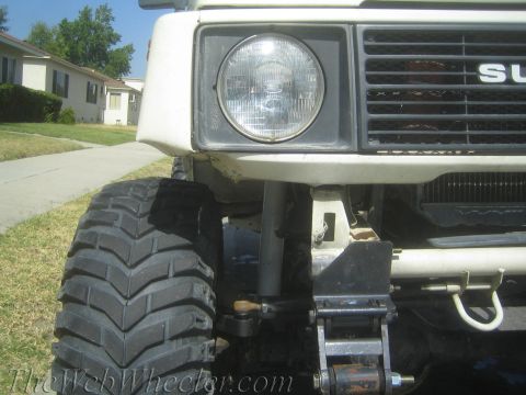 1987 Suzuki Samurai - Front view of a white 1987 Suzuki Samurai, large off-road tires and the prominent 'SUZUKI' grille badge.