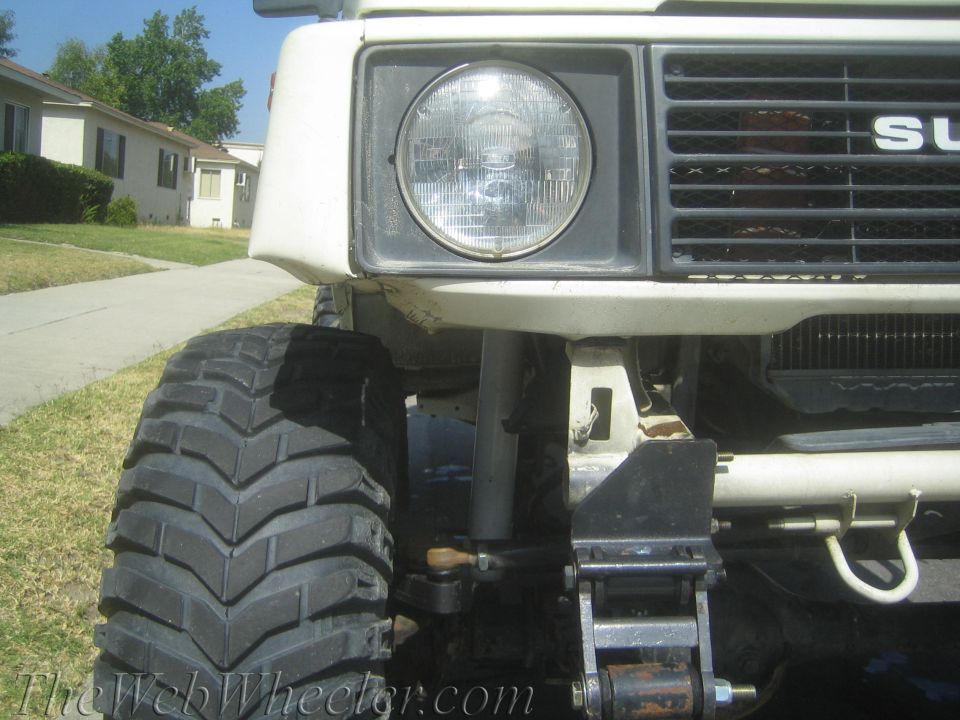 White 1987 Suzuki Samurai front end with large off-road tires and visible 'SUZUKI' badge