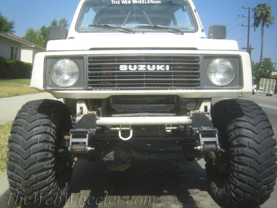 1987 Suzuki Samurai front view with large off-road tires and prominent SUZUKI grille