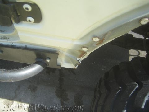 1987 Suzuki Samurai - Detail shot of a vehicle's lower body panel, showing some rust and a large off-road tire.