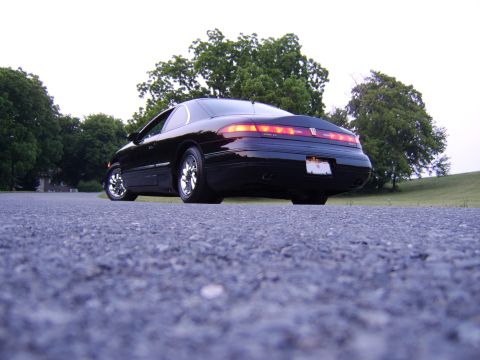 1996 Mercury Grand Marquis - Rear view of a black coupe parked on asphalt with trees in the background.