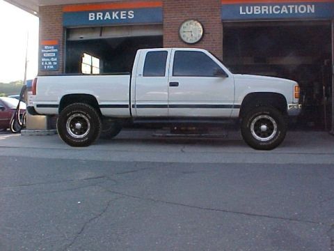2000 Chevrolet Tahoe - A white pickup truck is parked in front of a service bay at a garage.