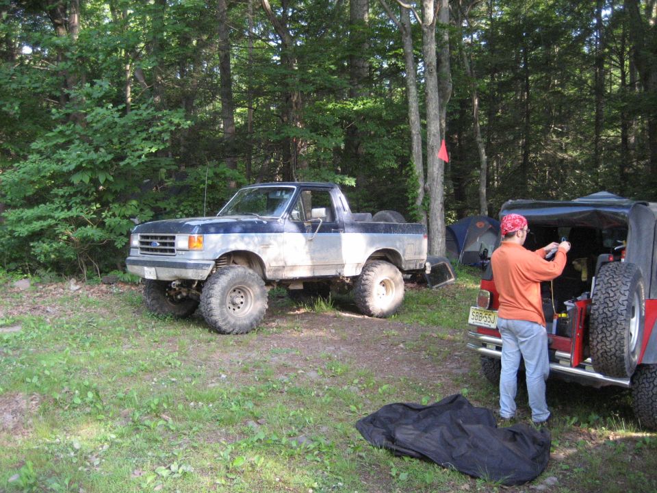1991 Ford Bronco parked next to a Jeep at a campsite