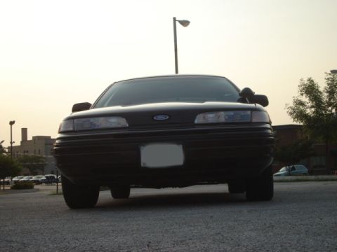 1992 Ford Crown Victoria - A black 1992 Ford Crown Victoria is shown from the front, parked outdoors with buildings and trees in the background.