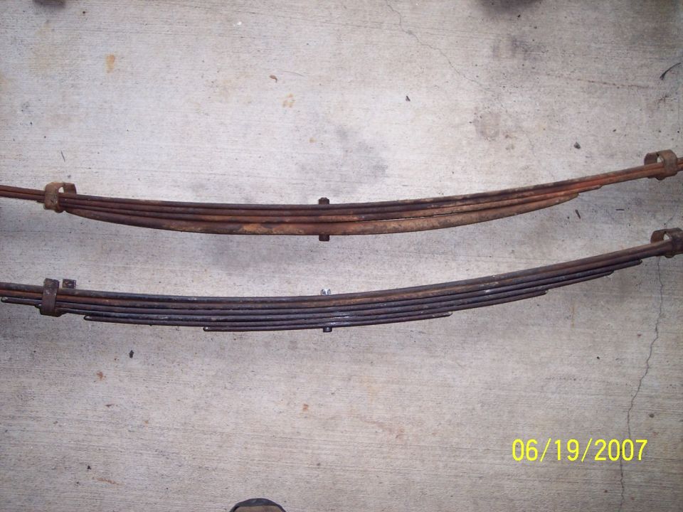 Two rusty leaf springs on a concrete surface