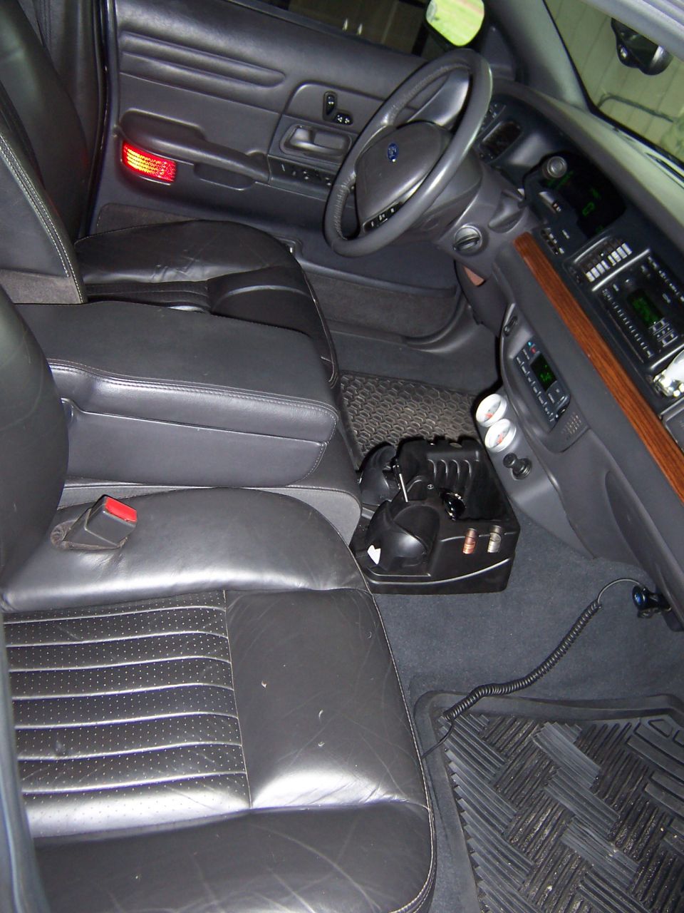 Front seats and dashboard of a 2001 Ford Crown Victoria. Black leather seats and black dashboard with wood trim