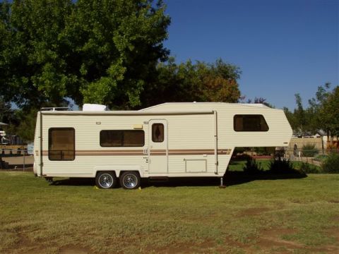 2000 Ford F-250 - A side view of a travel trailer with multiple windows and a raised front section.