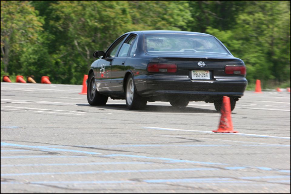 Black 1994 Chevrolet Impala SS driving on a track with cones