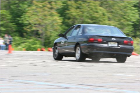 2001 Mercury Grand Marquis - A black sedan navigates an autocross course, kicking up dust from the asphalt.