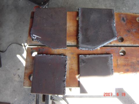 1993 Ford Bronco - Four metal pieces with jagged edges are laid out on a wooden surface.