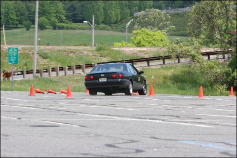 2001 Mercury Grand Marquis - A black sedan is seen from the rear on a paved course with orange cones.