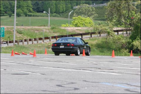 2001 Mercury Grand Marquis - A black sedan navigates a course marked by orange cones on a sunny day.