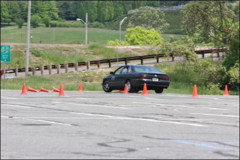 2001 Mercury Grand Marquis - A dark sedan is seen from the rear on a paved course marked with orange cones, likely during a timed event.