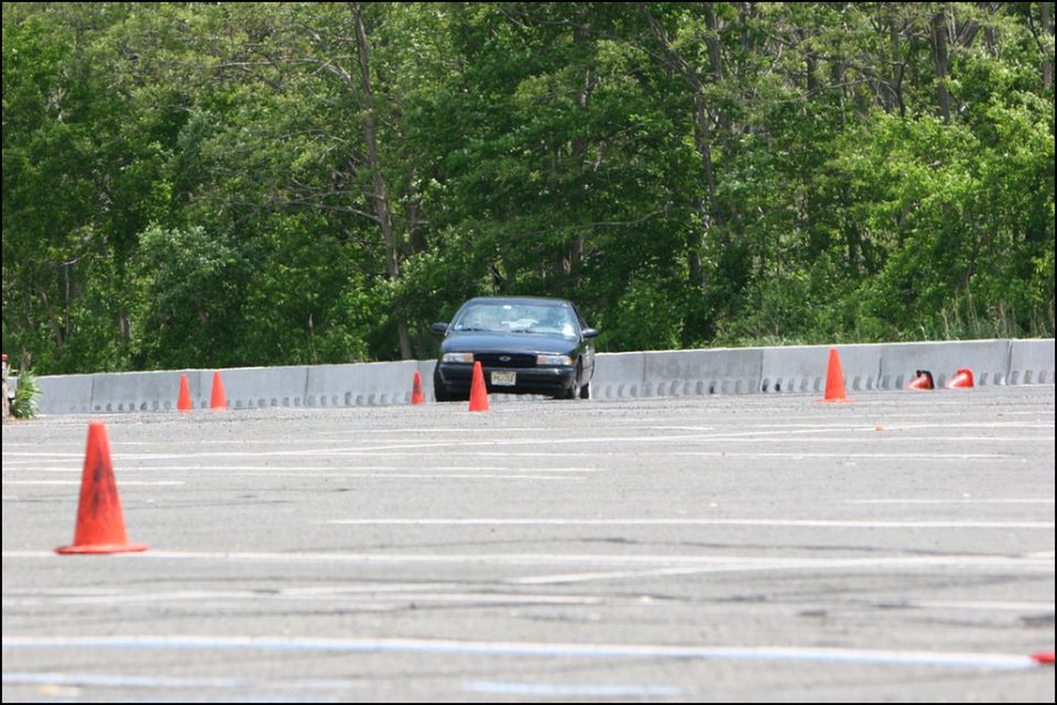Dark sedan navigating an autocross course with orange cones